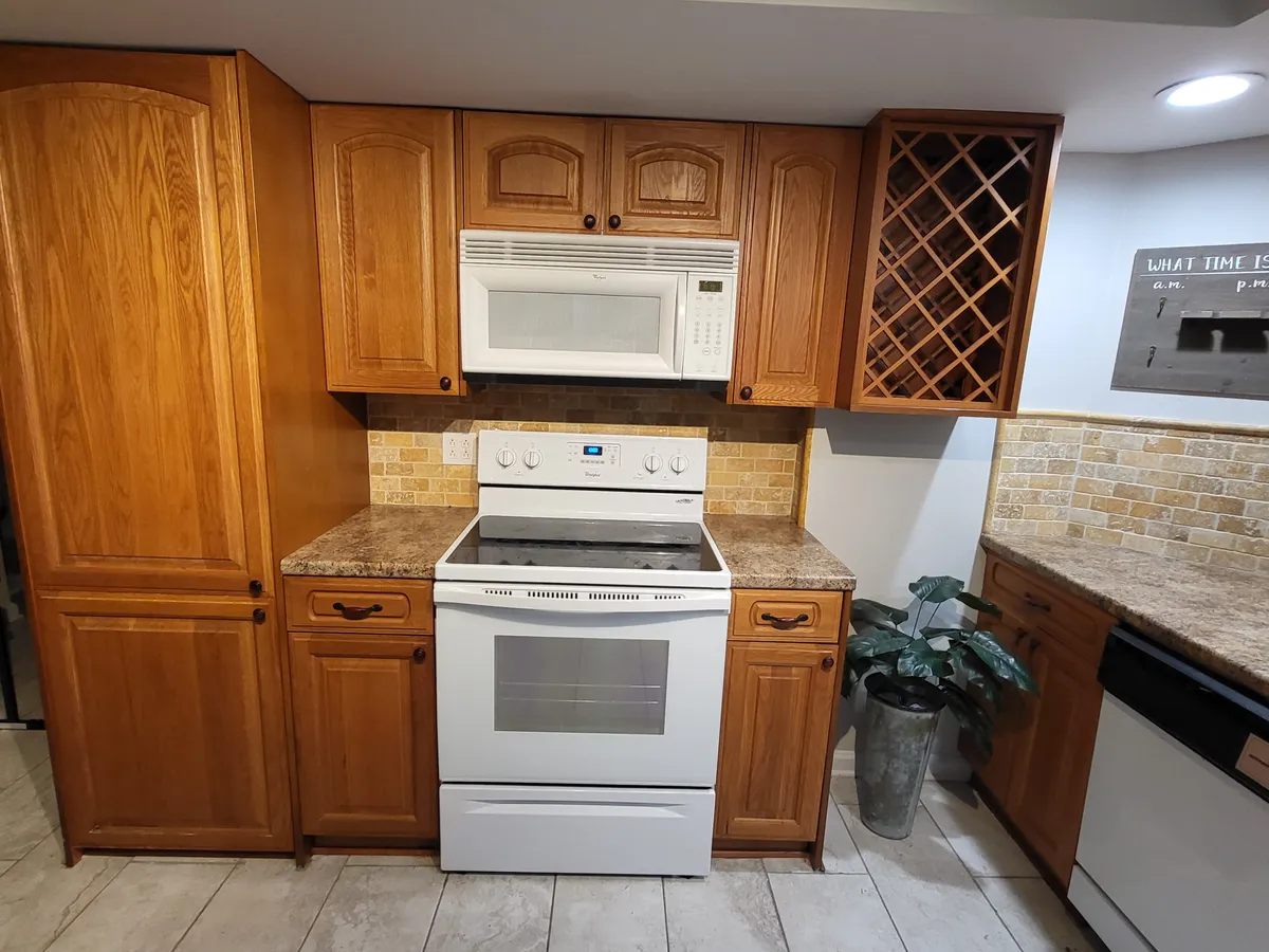 A view of the kitchen area with cabinetry, a built-in oven, microwave, wine rack, and decorative touches like a potted plant. The countertop is clear and ready for use, with full-sized appliances on display, signaling readiness for serious cooking and convenience for extended stays or busy guests.
